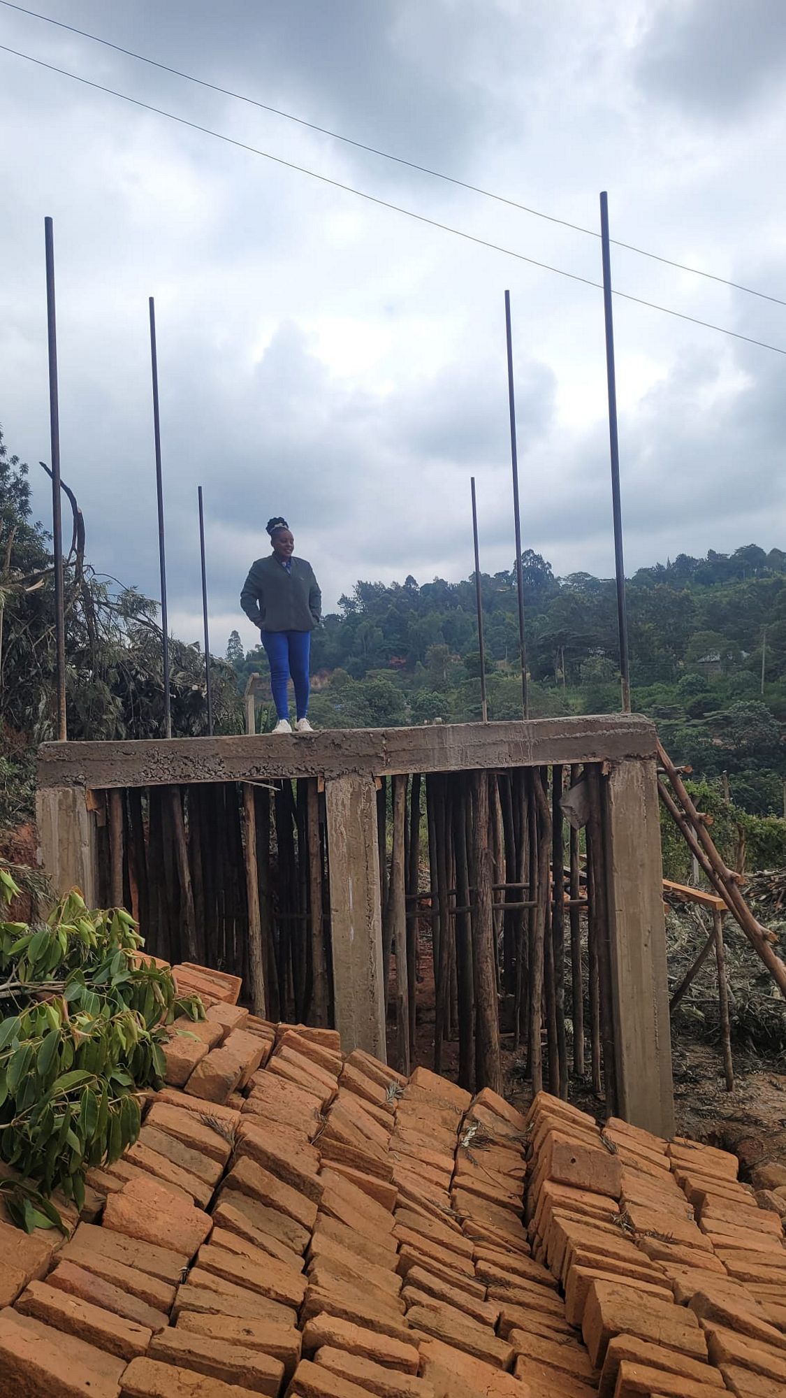 Young woman standing on top of new home structure in Africa